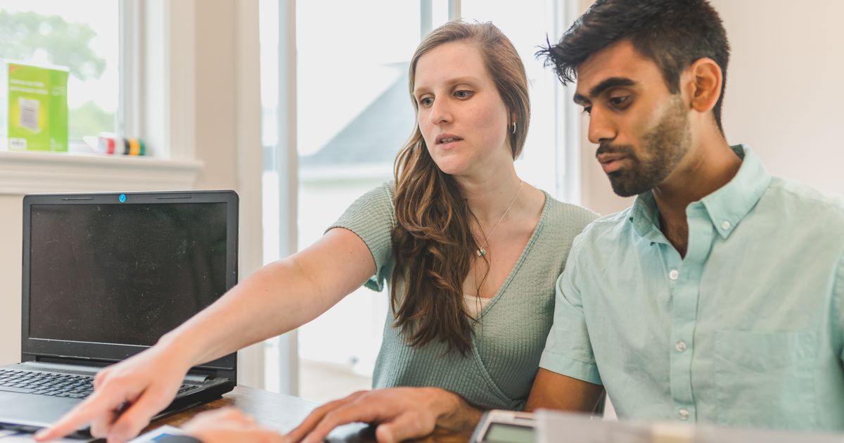 Twee mensen bekijken samen rustig documenten op een laptop aan een bureau bij het maken van afspraken over de woning