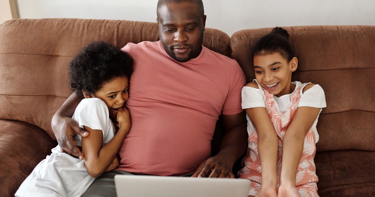 Vader zit met zijn twee kinderen op de bank achter een laptop