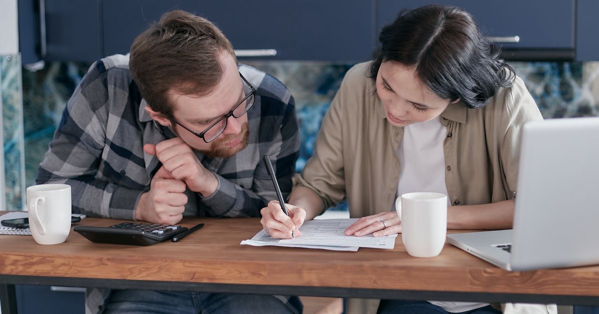 Man en vrouw bekijken samen aan de keukentafel financiële papieren voor hun online echtscheiding