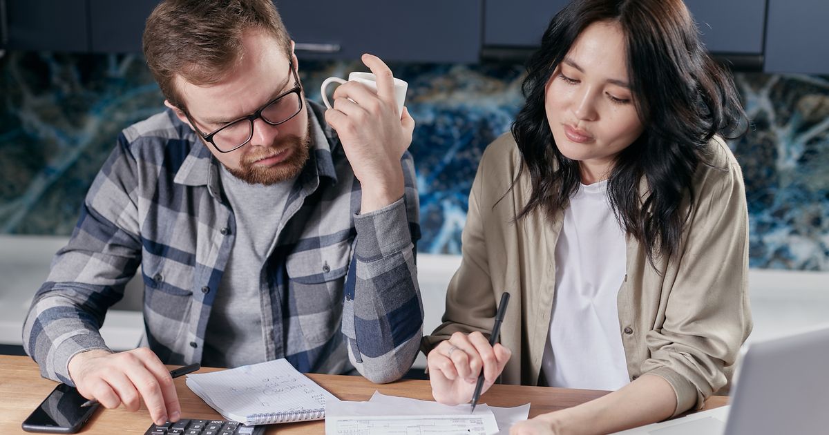 Man en vrouw bekijken samen financiële documenten en een berekening aan de keukentafel