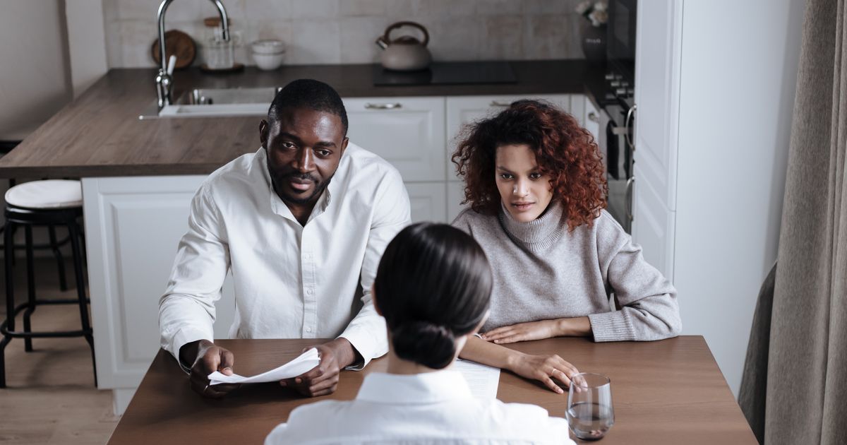 Man en vrouw bespreken samen de afspraken voor hun online echtscheiding met een adviseur aan tafel