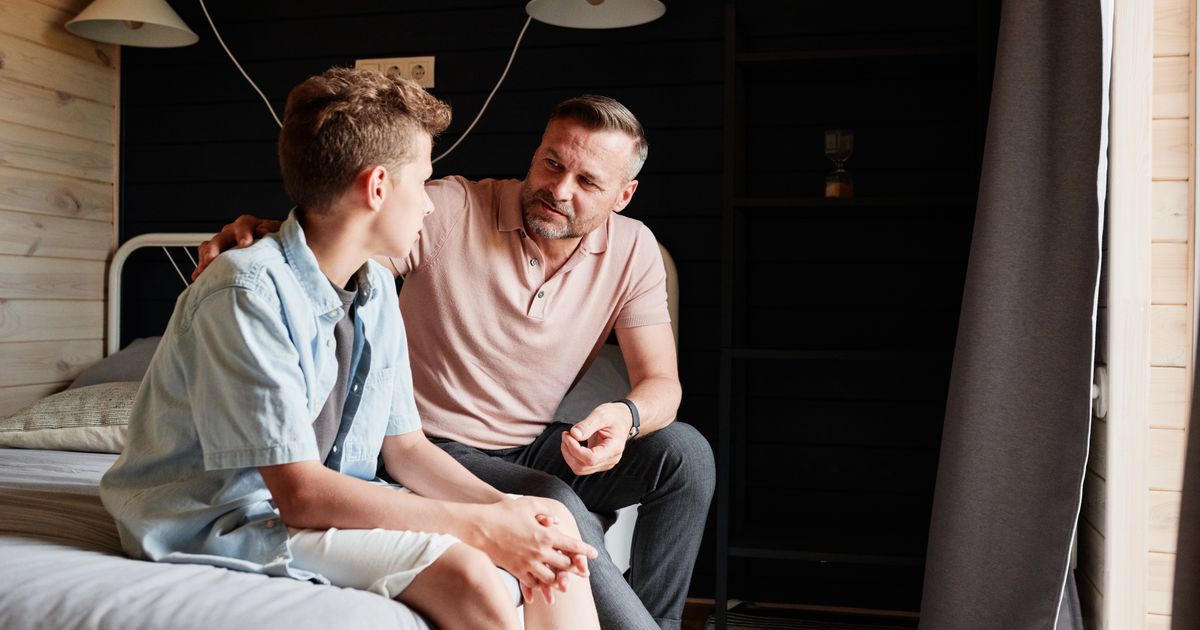 Vader en tienerzoon hebben een rustig gesprek, als beeld bij het hoorrecht van kinderen bij de online echtscheiding